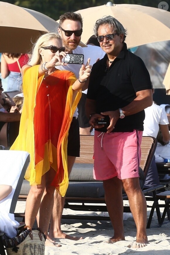 David Guetta et sa compagne Jessica Ledon, qui porte un diamant à l'annulaire gauche, passent du bon temps sur la plage en compagnie de leur petit chien. Miami, le 23 novembre 2018.