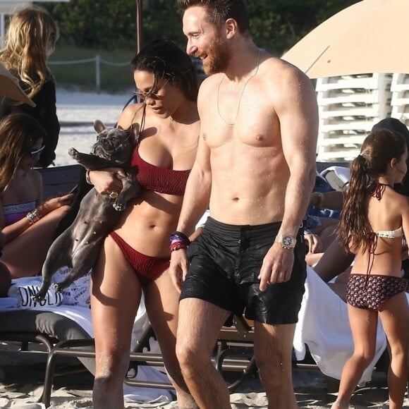 David Guetta et sa compagne Jessica Ledon, qui porte un diamant à l'annulaire gauche, passent du bon temps sur la plage en compagnie de leur petit chien. Miami, le 23 novembre 2018.