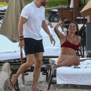 David Guetta et sa compagne Jessica Ledon, qui porte un diamant à l'annulaire gauche, passent du bon temps sur la plage en compagnie de leur petit chien. Miami, le 23 novembre 2018.