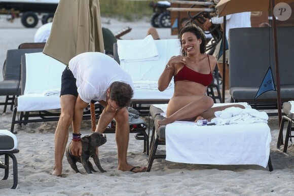 David Guetta et sa compagne Jessica Ledon, qui porte un diamant à l'annulaire gauche, passent du bon temps sur la plage en compagnie de leur petit chien. Miami, le 23 novembre 2018.