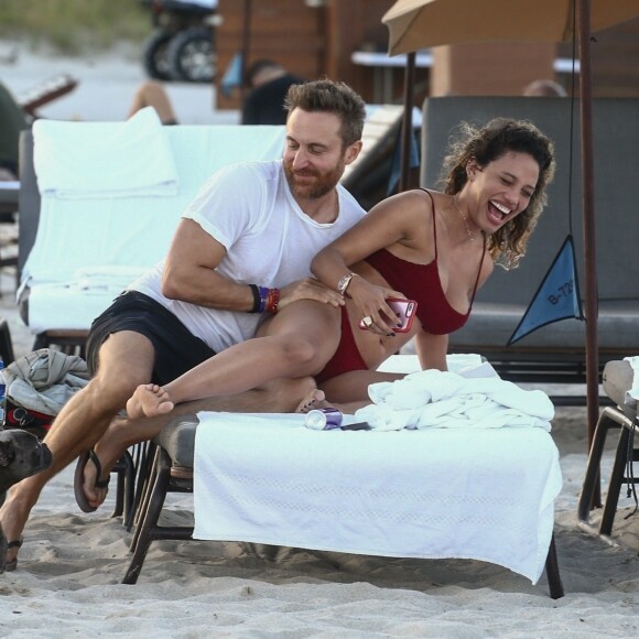 David Guetta et sa compagne Jessica Ledon, qui porte un diamant à l'annulaire gauche, passent du bon temps sur la plage en compagnie de leur petit chien. Miami, le 23 novembre 2018.