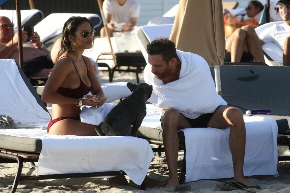 David Guetta et sa compagne Jessica Ledon, qui porte un diamant à l'annulaire gauche, passent du bon temps sur la plage en compagnie de leur petit chien. Miami, le 23 novembre 2018.