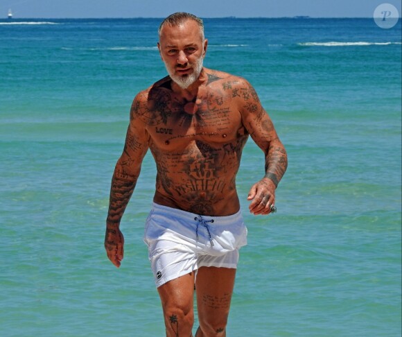 Exclusif - Gianluca Vacchi passe la journée en compagnie d'une mystérieuse inconnue sur la plage de Miami. Alors que sa carrière musicale vient de prendre un nouveau tournant, l'Italien aux 11 millions d'abonnés sur Instagram peaufine son bronzage sur les plages de Miami. Gianluca est actuellement avec Sharon Fonseca, un mannequin originaire du Venezuela, et file le parfait amour. La belle est la première fan de son copain musclé, puisqu'elle n'a pas hésité à partager des extraits de sa nouvelle chanson avec sa propre communauté Instagram. On peut d'ailleurs l'apercevoir dans les extraits du clip qui accompagne le titre Love. Le 22 avril 2019  For germany call for price Exclusive - Italian millionaire, DJ, actor, fitness guru, and Instagram star Gianluca Vacchi was pictured as he hit the beach in Miami with a beautiful blonde mystery woman. The 51-year-old was in his usual amazing shape as he showed off his sexy tan tattooed figure. He was also mobbed by fans for selfies when coming out of the water. He was very recently romantically linked to beautiful Venezuelan model Sharon Fonseca. 22nd april 201922/04/2019 - Miami