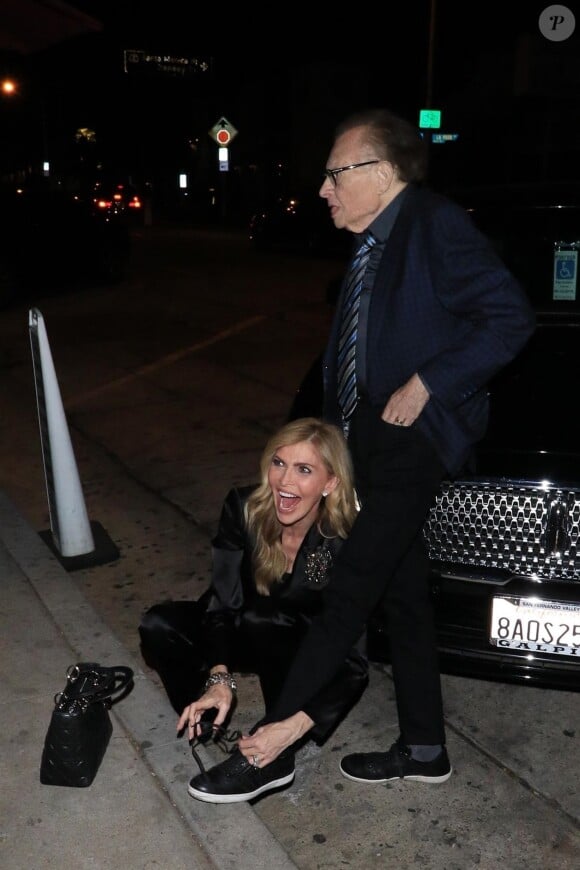 Shawn King, la femme de Larry King, lui refait ses lacets assise par terre devant l'entrée du restaurant Craig de West Hollywood le 15 janvier 2018.