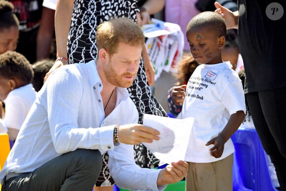 Le prince Harry, duc de Sussex, et Meghan Markle, duchesse de Sussex, arrivent main dans la main en visite dans le township de Nyanga en Afrique du Sud le 23 septembre 2019.