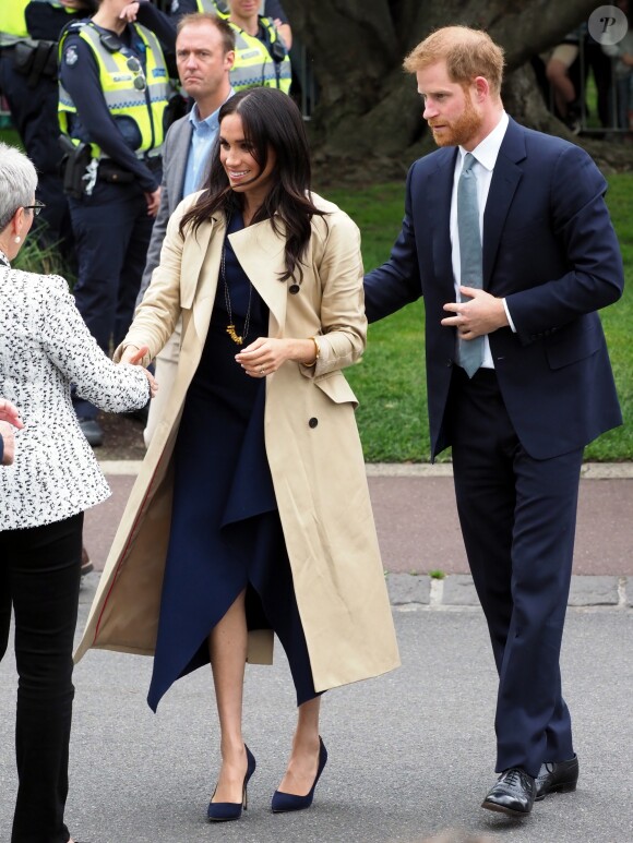 Le prince Harry, duc de Sussex, et Meghan Markle, en trench-coat Martin Grant, vont à la rencontre de la foule venue les accueillir, lors de la visite des jardins botaniques de Melbourne, le 18 octobre 2018.