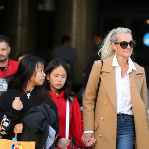 Exclusif - Laeticia Hallyday et ses filles Jade et Joy arrivent à l'aéroport LAX de Los Angeles en provenance de Paris, le samedi 11 janvier 2020 dans l'après-midi. Un chauffeur les attendait à leur arrivée. Laeticia lui fait signe, le salue, puis le suit en compagnie de ses filles jusqu'à la voiture. Deux porteurs poussent ses bagages.