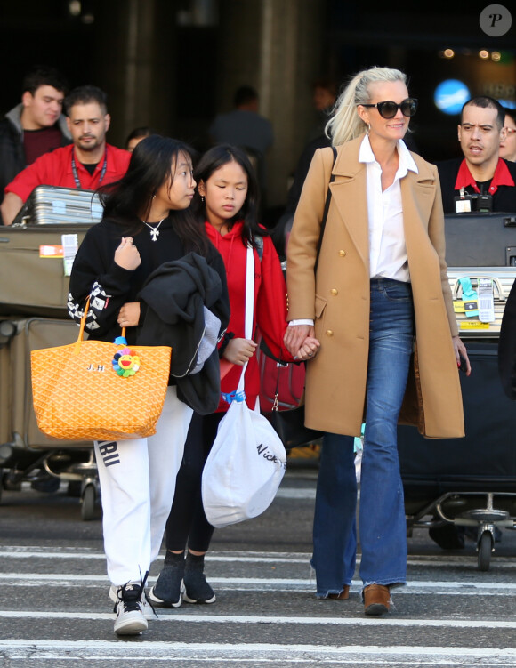 Exclusif - Laeticia Hallyday et ses filles Jade et Joy arrivent à l'aéroport LAX de Los Angeles en provenance de Paris, le samedi 11 janvier 2020 dans l'après-midi. Un chauffeur les attendait à leur arrivée. Laeticia lui fait signe, le salue, puis le suit en compagnie de ses filles jusqu'à la voiture. Deux porteurs poussent ses bagages.