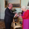 La reine Elizabeth II d'Angleterre se voit remettre la première Médaille en Or de l'Ordre de St John par le professeur Mark Compton lors d'une audience au palais de Buckingham à Londres le 11 mars 2020. En pleine pandémie du coronavirus, la souveraine n'a pas hésité à serrer la main de son visiteur.