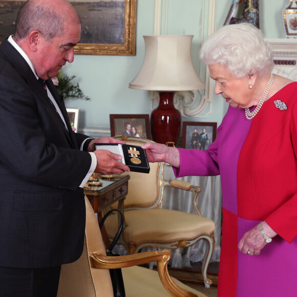La reine Elizabeth II d'Angleterre se voit remettre la première Médaille en Or de l'Ordre de St John par le professeur Mark Compton lors d'une audience au palais de Buckingham à Londres le 11 mars 2020. En pleine pandémie du coronavirus, la souveraine n'a pas hésité à serrer la main de son visiteur.