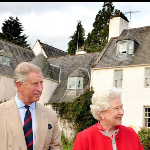 Le prince Charles et la reine Elizabeth II en 2009 dans les jardins de Birkhall en Ecosse avec l'auteur William Shawcross présentant à la souveraine sa biographie de la reine mère.