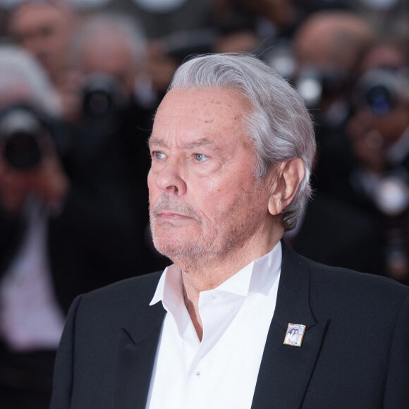 Alain Delon (Palme d'Or d'Honneur du 72ème festival de Cannes avec un badge Paris Match d'une ancienne couverture du magazine titrant "Alain Delon, mes deux amours, Rosalie et Anouchka)