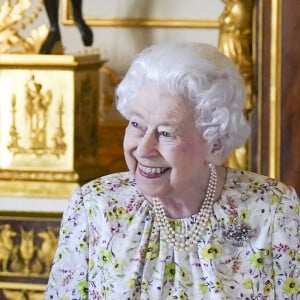 La reine Elizabeth II d'Angleterre parcourt l'exposition d'objets de la société d'artisanat britannique Halcyon Days, pour marquer son jubilé de platine, au château de Windsor, le 23 mars 2022.