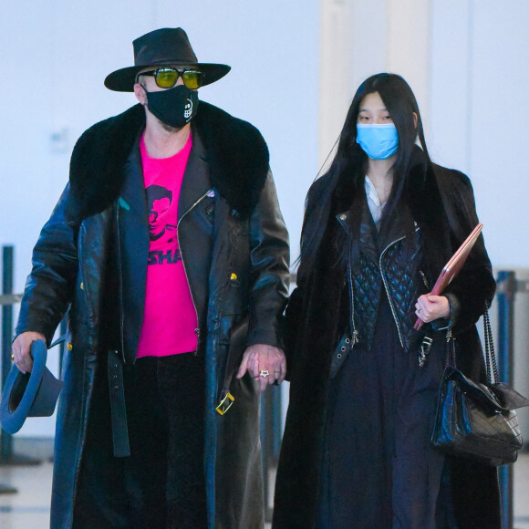 Nicolas Cage et sa femme Riko Shibata arrivent, main dans la main, à l'aéroport JFK à New York, le 27 novembre 2021.