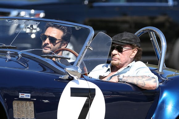 Johnny Hallyday accompagné de Maxim Nucci (Yodelice), arrive au restaurant "Soho House" à Malibu, au volant de son cabriolet AC Cobra marqué de son chiffre porte-bonheur, le numéro 7. Malibu, le 09 mars 2017.