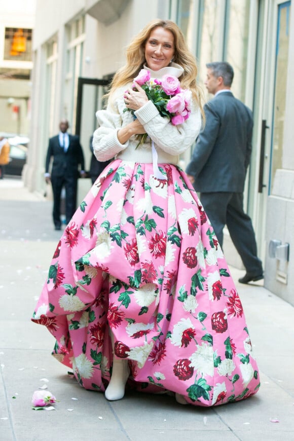 Céline Dion rayonnante et très souriante dans un ensemble pull écru et jupe bouffante fleurie salue ses fans à la sortie de son hôtel à New York, le 8 mars 2020
