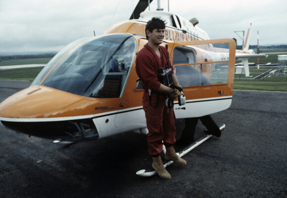 Archives - En France, Philippe de Dieuleveult devant l'hélicoptère, vêtu de sa combinaison rouge, portant son casque d'écoute et son poste émetteur lors de l'émission La chasse aux trésors en mai 1983