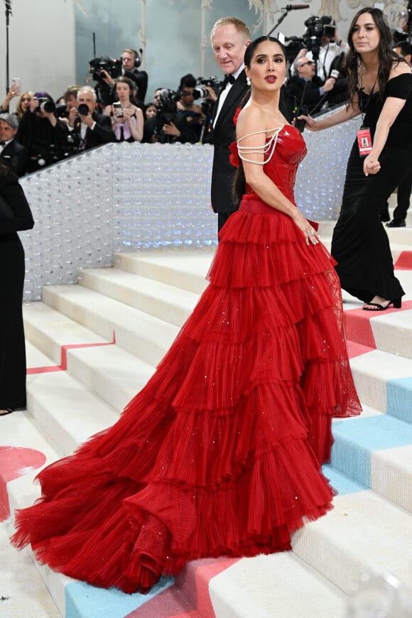 Vêtue d'une robe rouge ultra sexy, elle est apparue dans un bustier décolleté, laissant apparaître sa poitrine gonflée. Le haut de sa robe, réalisé en cuir et aux bretelles perlées, était mis en avant par la longue jupe en tulle cintrée à la taille.
Salma Hayek - Les célébrités arrivent à la soirée du "MET Gala 2023" à New York, le 1er mai 2023. 