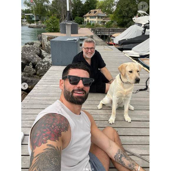 Hugo Manos prend la photo, apparaissant ainsi en premier plan, tandis que Laurent Ruquier se dévoile souriant dans le fond, au côté de leur chien Tigane.
Laurent Ruquier lors de vacances en Suisse avec son jeune compagnon Hugo Manos - Instagram, 5 juillet 2023.