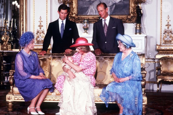 Elle avait lancé qu'heureusement le jeune garçon n'avait pas les mêmes oreilles que son père ! 
La reine Elisabeth II d'Angleterre et le prince Philip, duc d'Edimbourg, leur fils le prince Charles et sa femme la princesse Diana, avec leur fils le prince William, et la reine mère, le jour du baptème du prince William. Drawing Room du palais de Buckingham à Londres. Le 4 août 1982 