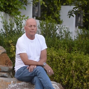 Exclusif - Bruce Willis est assis pieds nus sur un rocher et regarde passer les voitures sur Sunset Boulevard à Los Angeles, le 22 septembre 2019. Il porte un jean et un t-shirt blanc. 