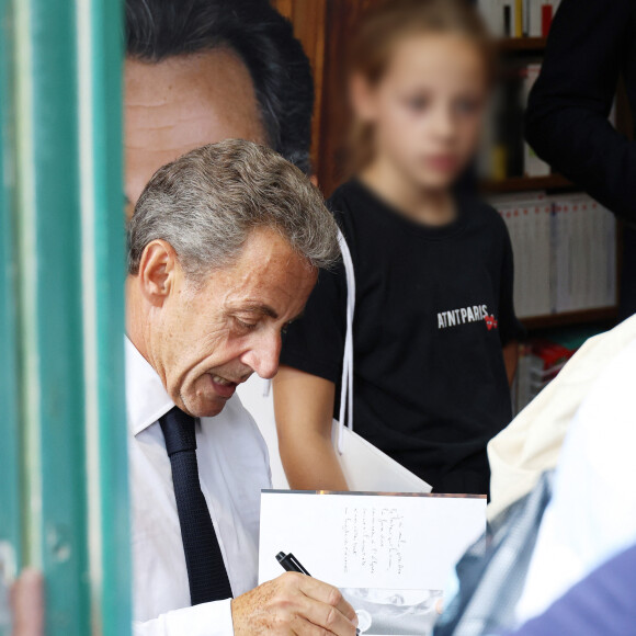 L'ancien président de la République française Nicolas Sarkozy dédicace son livre "Le temps des Combats" sous l'oeil attentif de sa fille Giulia à la Librairie du Marché à Deauville, France, le 1er septembre 2023. © Denis Guignebourg/Bestimage 