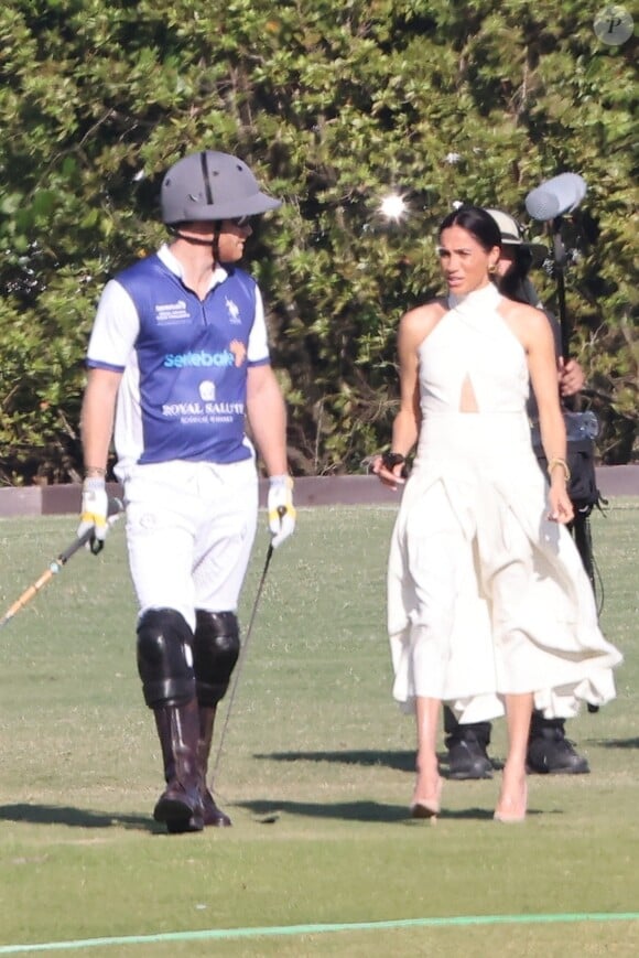 Une décision du couple qui interpelle à l'international.
Palm Beach, FL - Meghan Markle, en robe blanche et talons hauts, arrive main dans la main avec le prince Harry au Royal Salute Polo Challenge à Miami.