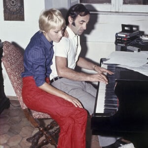 L'auteur-compositeur-interprète français d'origine arménienne Charles Aznavour joue un thème au piano ; à côté de lui est assise sa troisième épouse, la Suédoise Ulla Thorsell, qui caresse du pied un caniche blanc, tandis qu'en gros plan se détache un clavier. Italie, 1968. Photo de Giorgio Ambrosi/Mondadori Portfolio via ZUMA Press/ABACAPRESS.COM