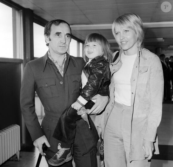 ...Purepeople se penche sur l'héritage du chanteur qui a eu trois épouses, dont Ulla, ici, qui fut sa dernière...Le chanteur français Charles Aznavour, vêtu d'une veste de style Norfolk et marchant avec une canne après s'être cassé la jambe en faisant du ski, arrive à Heathrow avec sa famille, sa troisième épouse Ulla et leur fille Katia, 3 ans. Il est à Londres pour un concert au London Palladium. Mai 1973 Photo par The Sun/News Licensing/ABACAPRESS.COM