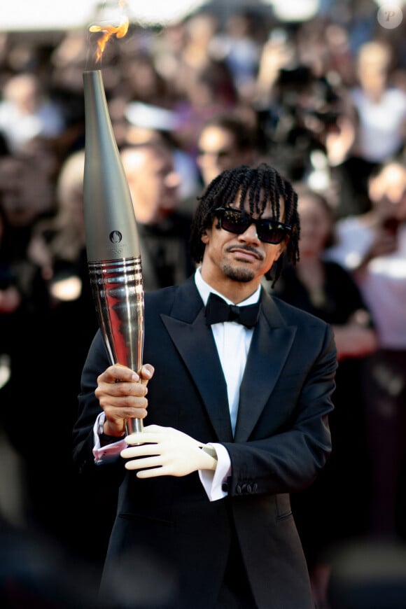 Nous avions pu le voir porter la flamme olympique lors du festival de Cannes.
Arnaud Assoumani et la flamme olympique - Montée des marches du film " Marcello Mio " lors du 77ème Festival International du Film de Cannes, au Palais des Festivals à Cannes. Le 21 mai 2024 © Norbert Scanella / Panoramic / Bestimage 