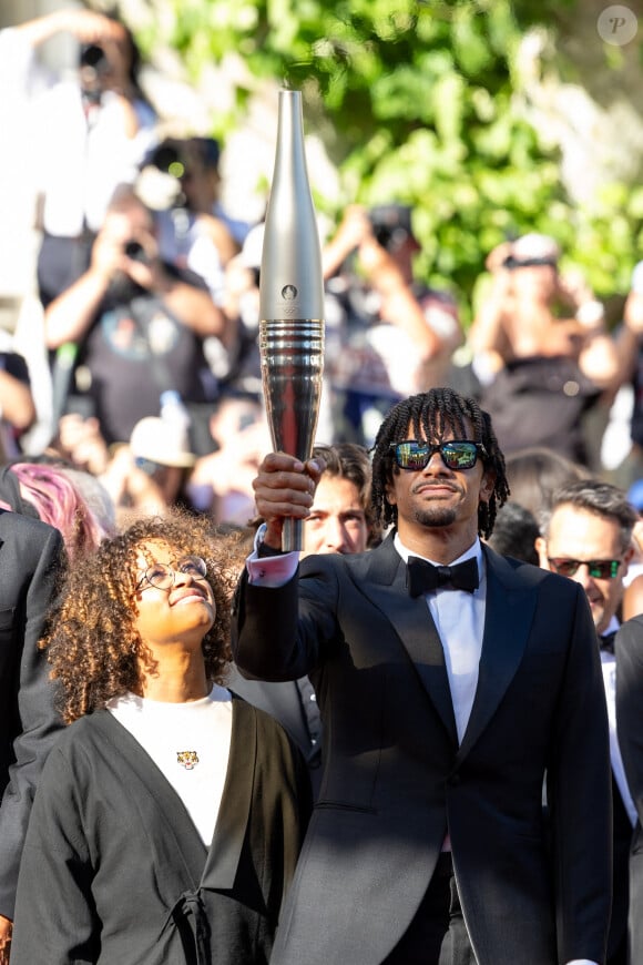 Nélia Barbosa, Arnaud Assoumani et la flamme olympique - Montée des marches du film " Marcello Mio " lors du 77ème Festival International du Film de Cannes, au Palais des Festivals à Cannes. Le 21 mai 2024 © Jacovides-Moreau / Bestimage 