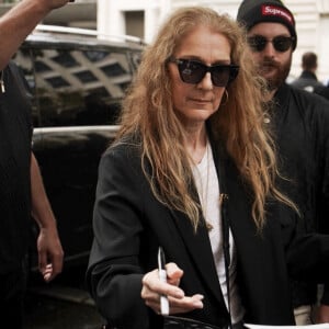 Paris, France - La chanteuse canadienne Céline Dion quitte son hôtel pour se rendre à l'aéroport, prenant le temps de saluer et de signer des autographes à la foule de fans qui l'attendent, montrant ainsi sa reconnaissance pour leur soutien.