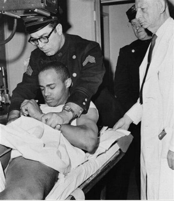 Thomas Hagan, peu après le meurtre de Malcolm X, écacué par la police après qu'il ait été roué de coups par la foule. À New York, le 21 février 1965