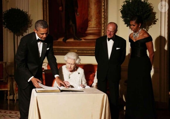 Barack, Michelle Obama et le duc d'Edimbourg entourent la reine qui signe le livre d'or de l'ambassade américain à Londres avant le grand dîner donné en son honneur, le 25 mai 2011.