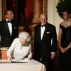 Barack, Michelle Obama et le duc d'Edimbourg entourent la reine qui signe le livre d'or de l'ambassade américain à Londres avant le grand dîner donné en son honneur, le 25 mai 2011.