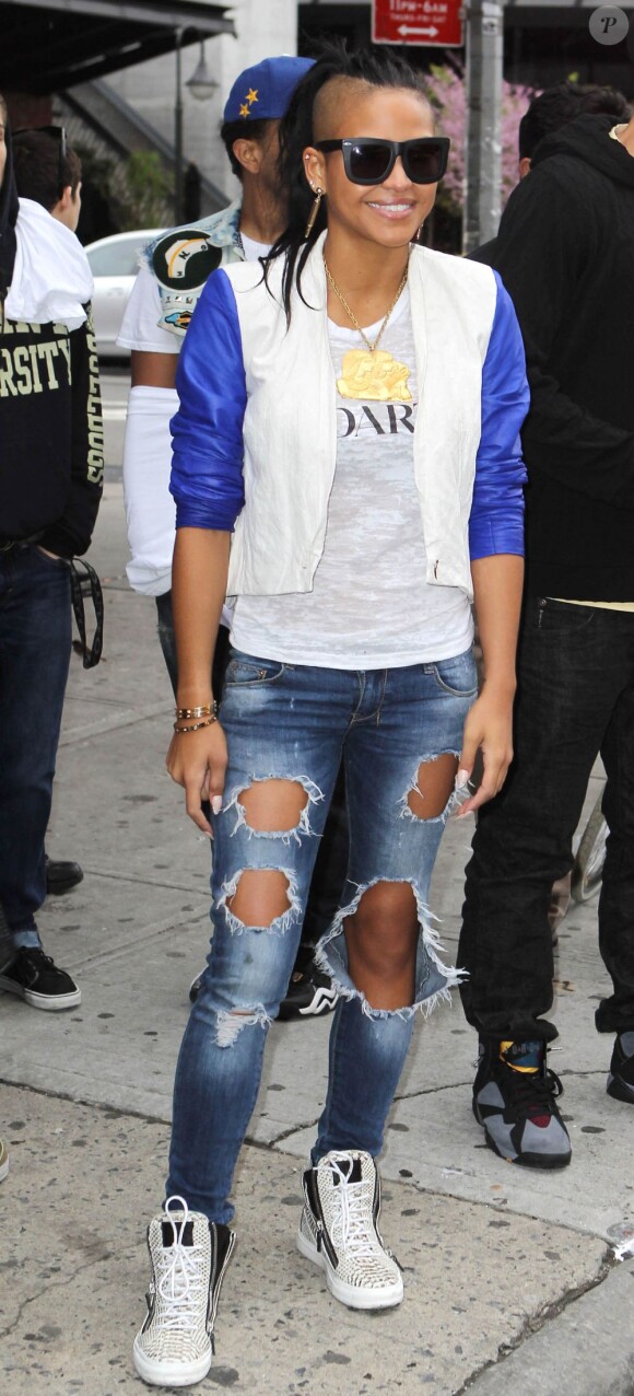 La chanteuse Cassie, souriante à New York, vêtue d'une veste courte sur un T-shirt Rodarte, un jean destroy et une paire de baskets Giuseppe Zanotti. Le 23 avril 2012.