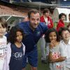 Fred Testo entouré d'enfants le 25 juin au Parc des Princes à Paris pour un match de foot au profit de l'association Plus Fort la Vie présidée par Jean-Claude Darmon