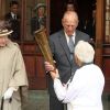 Le prince Philip soupèse la torche. La reine Elizabeth II et son mari le prince Philip ont accueilli au château de Windsor la flamme olympique, le 10 juillet 2012, lors du 53e jour du relais de la torche olympique, assistant au passage de témoin entre Gina Macgregor et Phil Wells.