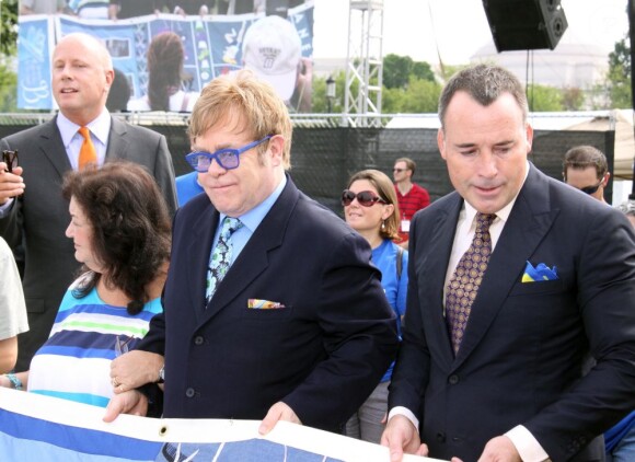Elton John et David Furnish tiennent un morceau du AIDS Memorial Quilt qui rend hommage aux victimes, en marge de l'ouverture de la 19e Conférence internationale sur le sida à Washington, le 23 juillet 2012.