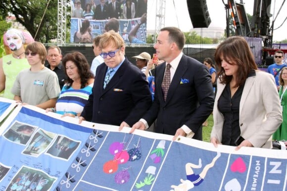 Elton John et David Furnish tiennent un morceau du AIDS Memorial Quilt qui rend hommage aux victimes, en marge de l'ouverture de la 19e Conférence internationale sur le sida à Washington, le 23 juillet 2012.