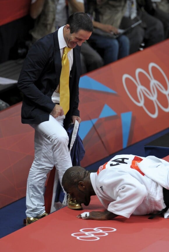 Teddy Riner embrasse les chaussures en or de son coach Benoit Campargue après avoir décroché l'or olympique le 3 août 2012 à Londres
