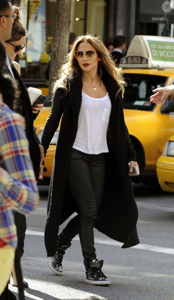 Jennifer Lopez, habillée d'un long gilet, d'un t-shirt blanc, d'un pantalon en cuir et de baskets Supra, arpentent les boutiques des quartiers de TriBeCa et SoHo. New York, le 11 septembre 2012.