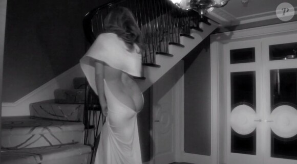 Kylie Minogue, habillée d'une robe blanche dos nu, expose sa superbe chute de reins dans une fausse pub réalisée par Katerina Jebb.