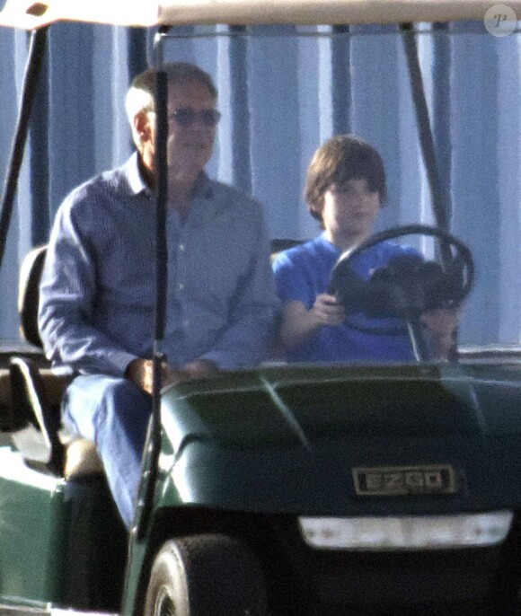 Harrison Ford, attentif pendant que son fils Liam conduit une petite golfette avant de prendre l'avion, le 25 novembre 2012.