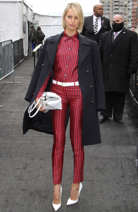 Karolina Kurkova stylée dans son manteau noir porté à l'italienne et son ensemble rayé accessoirisé d'une ceinture, d'un sac et de souliers blancs pour assister au défilé automne-hiver 2013 de Michael Kors. New York, le 10 février 2013.