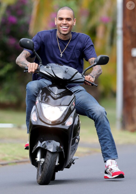 Chris Brown, souriant à Hawaï où il a rejoint Rihanna pour son anniversaire, fait du scooter sans casque. Le 21 février 2013.