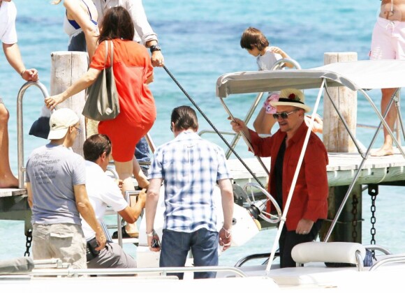 Le chanteur Bono, sa femme Alison Hewson (en robe rouge) et Larry Mullen (batteur du groupe U2, chemise bleue à carreaux) arrivent au Club 55, plage de Pampelonne à Ramatuelle, le 04 juillet 2013.