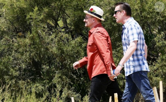 Le chanteur Bono, sa femme Alison Hewson (en robe rouge) et Larry Mullen (batteur du groupe U2, chemise bleue à carreaux) arrivent au Club 55, plage de Pampelonne à Ramatuelle, le 04 juillet 2013.