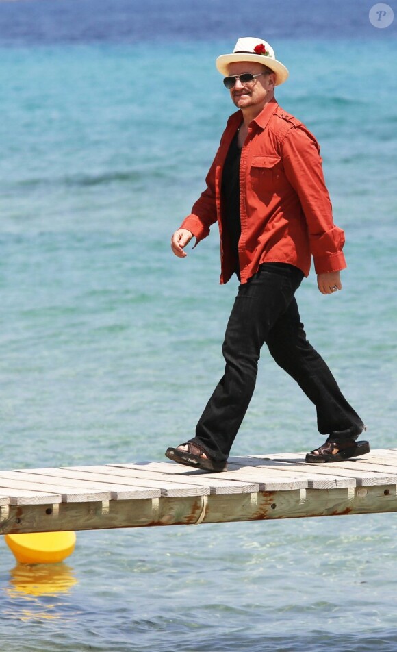 Le chanteur Bono, sa femme Alison Hewson (en robe rouge) et Larry Mullen (batteur du groupe U2, chemise bleue à carreaux) arrivent au Club 55, plage de Pampelonne à Ramatuelle, le 04 juillet 2013.