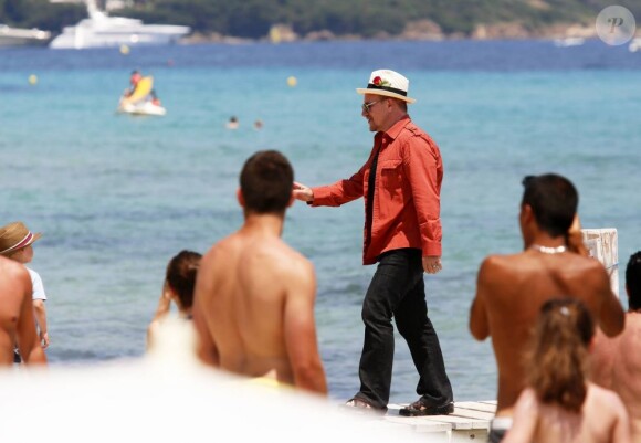 Le chanteur Bono, sa femme Alison Hewson (en robe rouge) et Larry Mullen (batteur du groupe U2, chemise bleue à carreaux) arrivent au Club 55, plage de Pampelonne à Ramatuelle, le 04 juillet 2013.